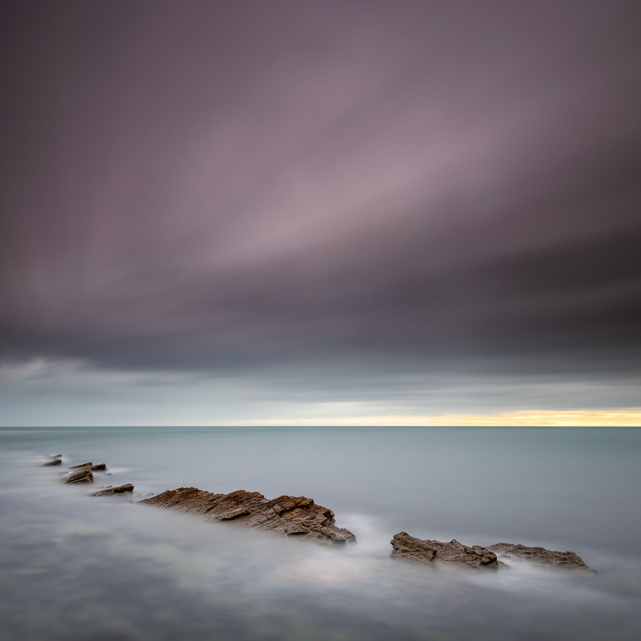 Peveril Point — long-exposure rocks receding into a calm sea beneath a muted sky