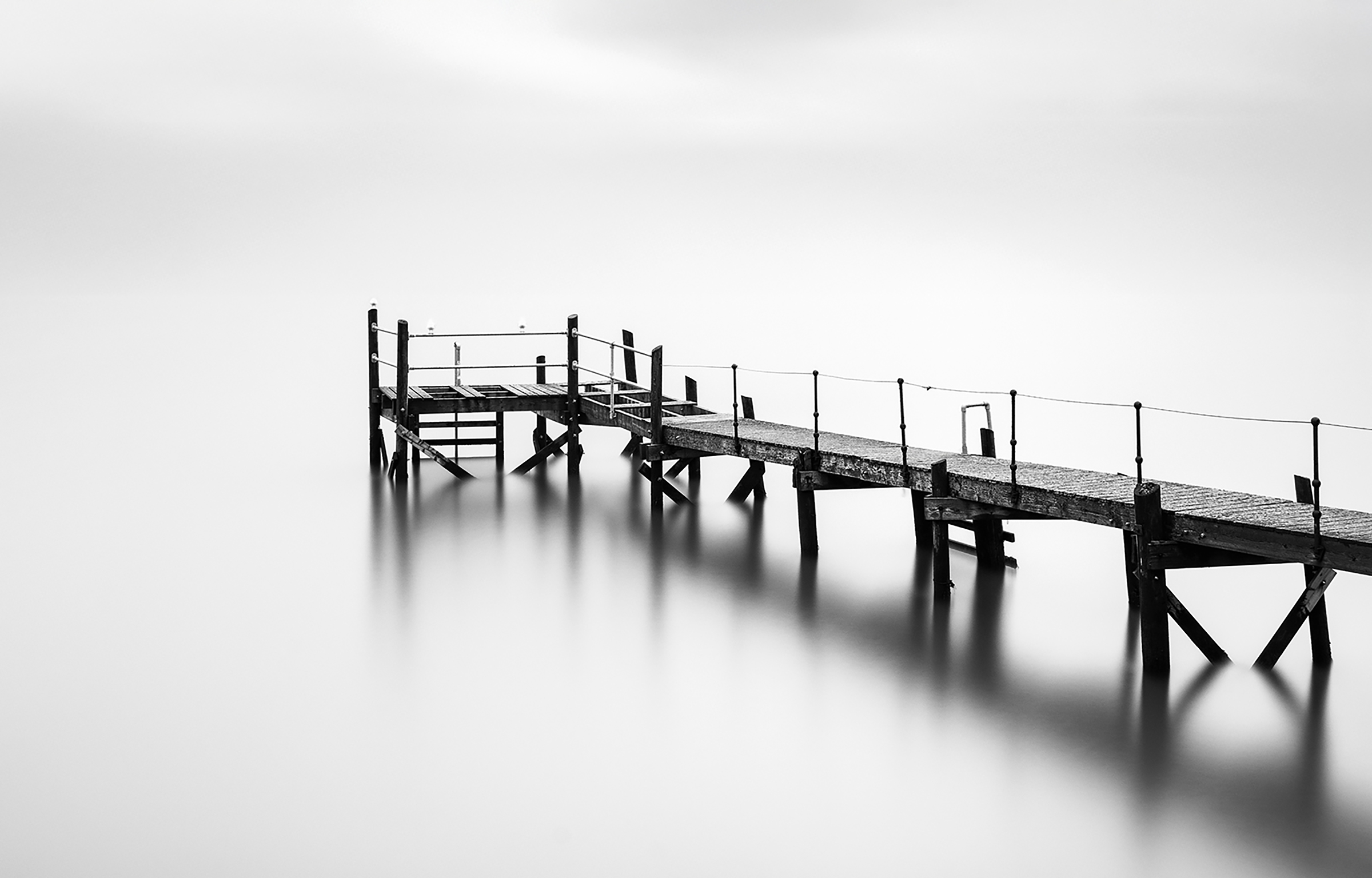 Kinnegar Jetty — a high-key study of a wooden jetty disappearing into quiet water
